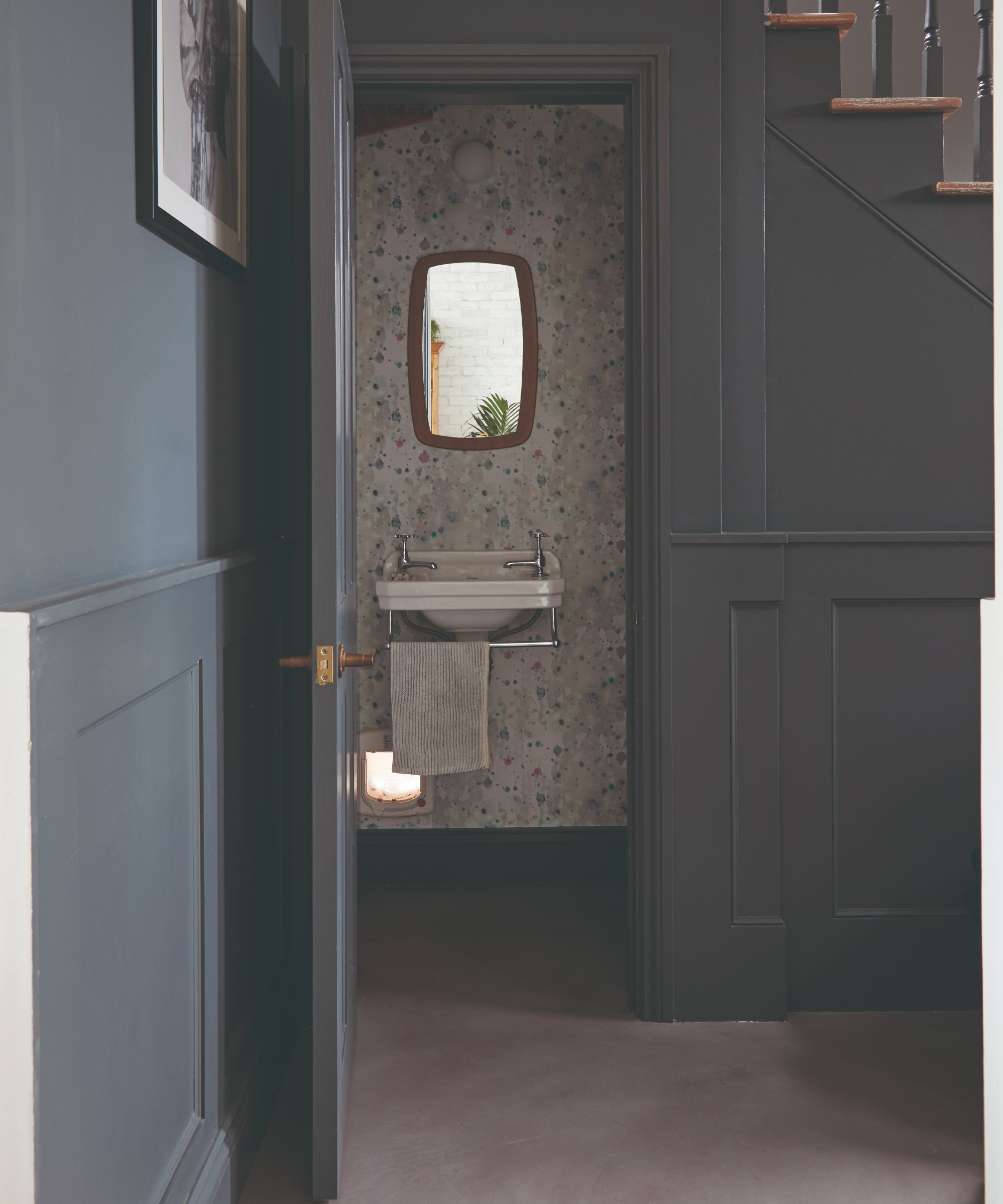 A hallway colour-drenched in a charcoal grey shade with the door to the downstairs toilet open