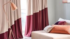 two-tone curtains with pale pink and dark pink, pink ottoman covered in pink cushions, with salmon-covered floor lamp