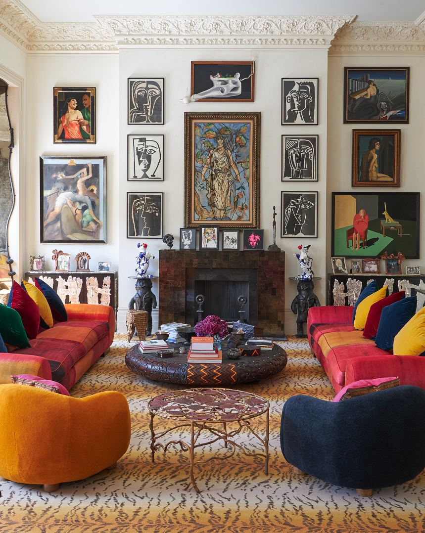 Pauline Karpidas's living room features colourful sofas, a circular, low coffee table, and many works of art hung on the walls