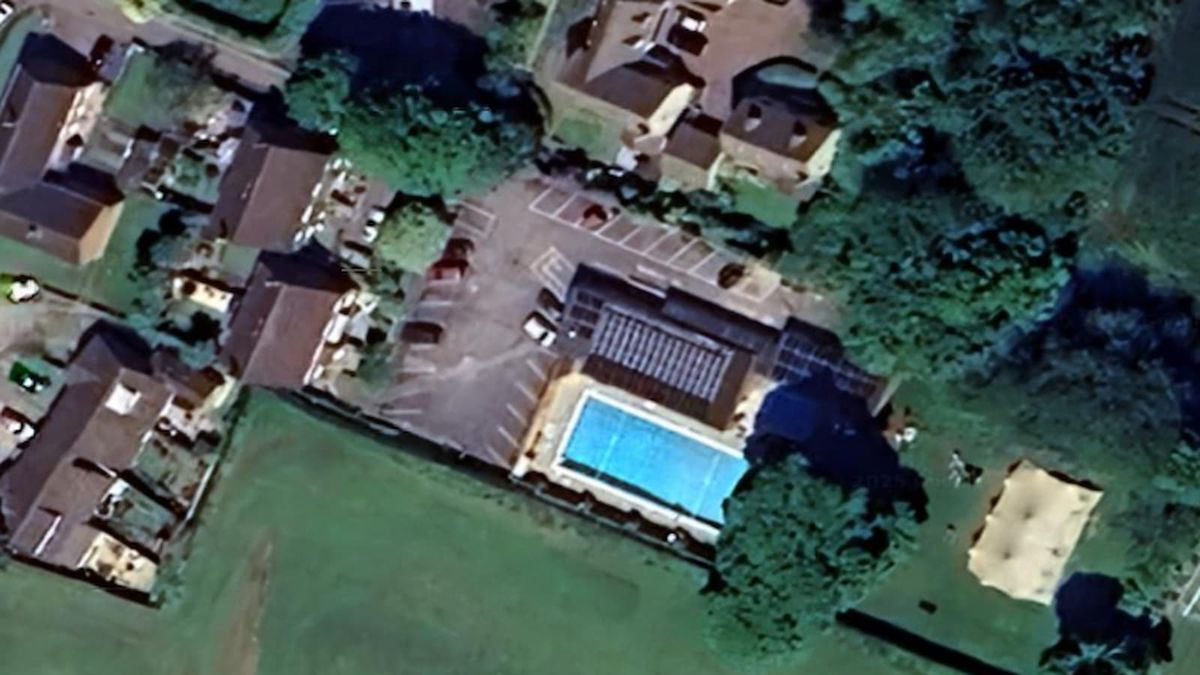 An overhead shot of a group of houses with a swimming pool in the middle