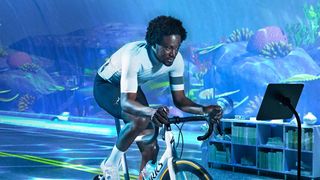 A man racing on a turbo trainer with an aquarium in the background