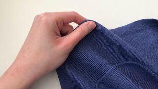 A cardigan being stretched by hand