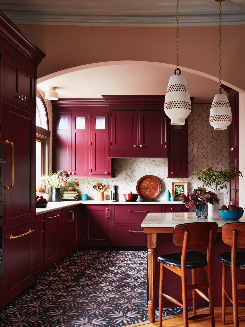 A kitchen with burgundy cabinets, and salmon pink walls