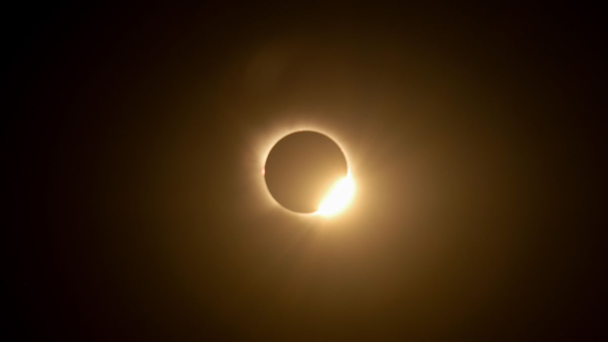 A totally eclipsed sun is pictured in a black sky.