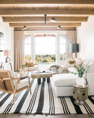 Black and white stiped rug, wooden ceiling and furniture with white cushioning, and walls
