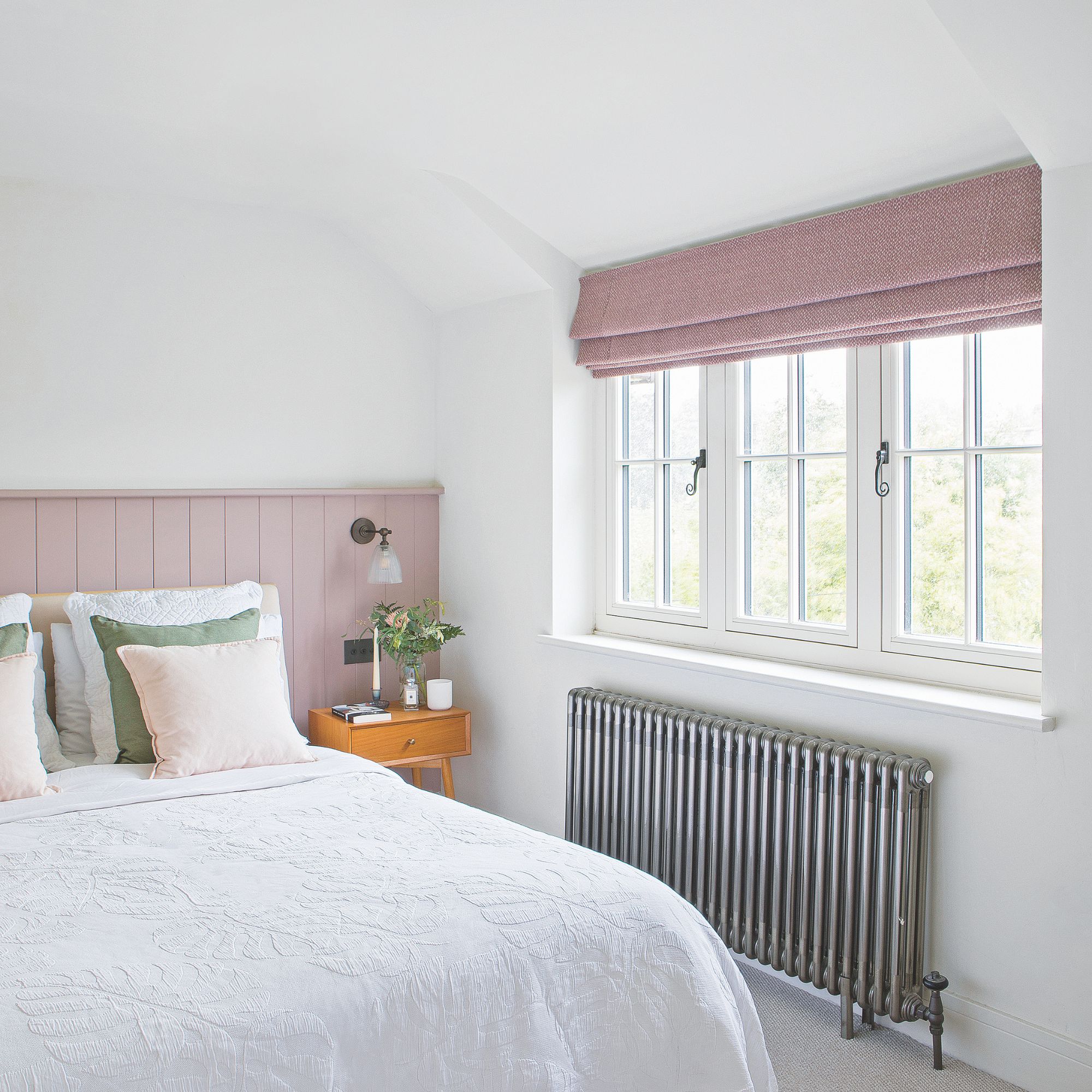 White painted bedroom with a bed covered in white bedding, with pink panelling behind it