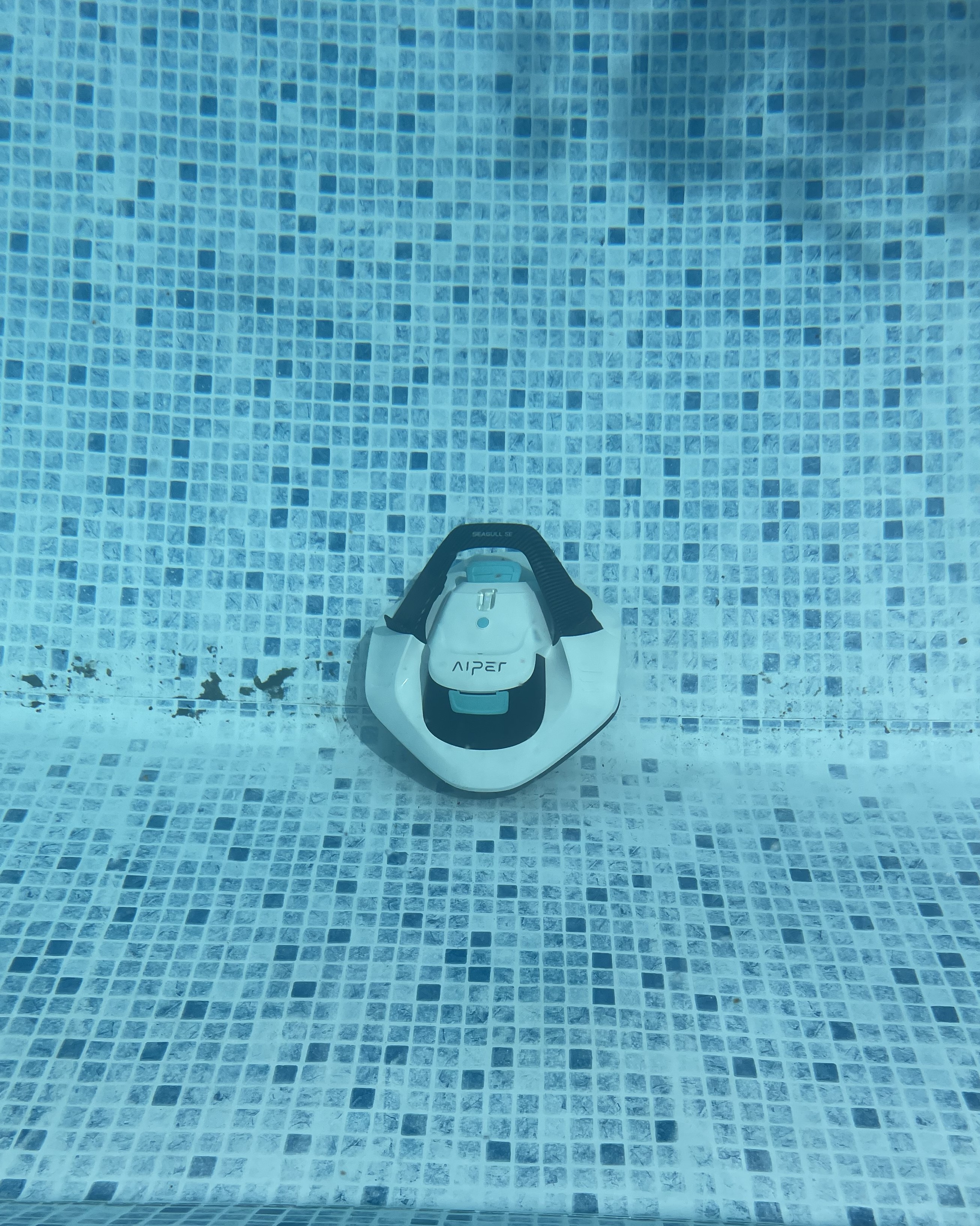 A robot pool cleaner sucking up dirt on the bottom of a pool floor