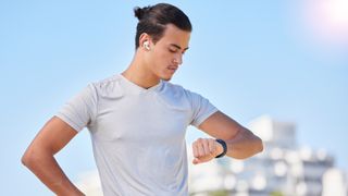 Man wearing earbuds checking sports watch during workout