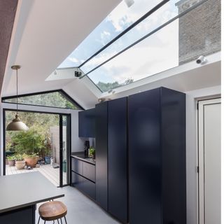 a kitchen with a long rooflight, navy blue kitchen cabinetry. plenty of storage and a kitchen island