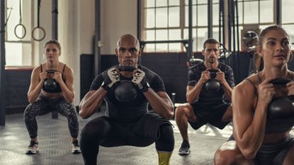 Group of people squatting with a kettlebell