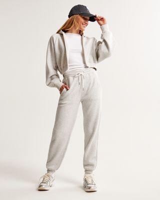 a model wears gray sweatpants with a matching cropped hoodie