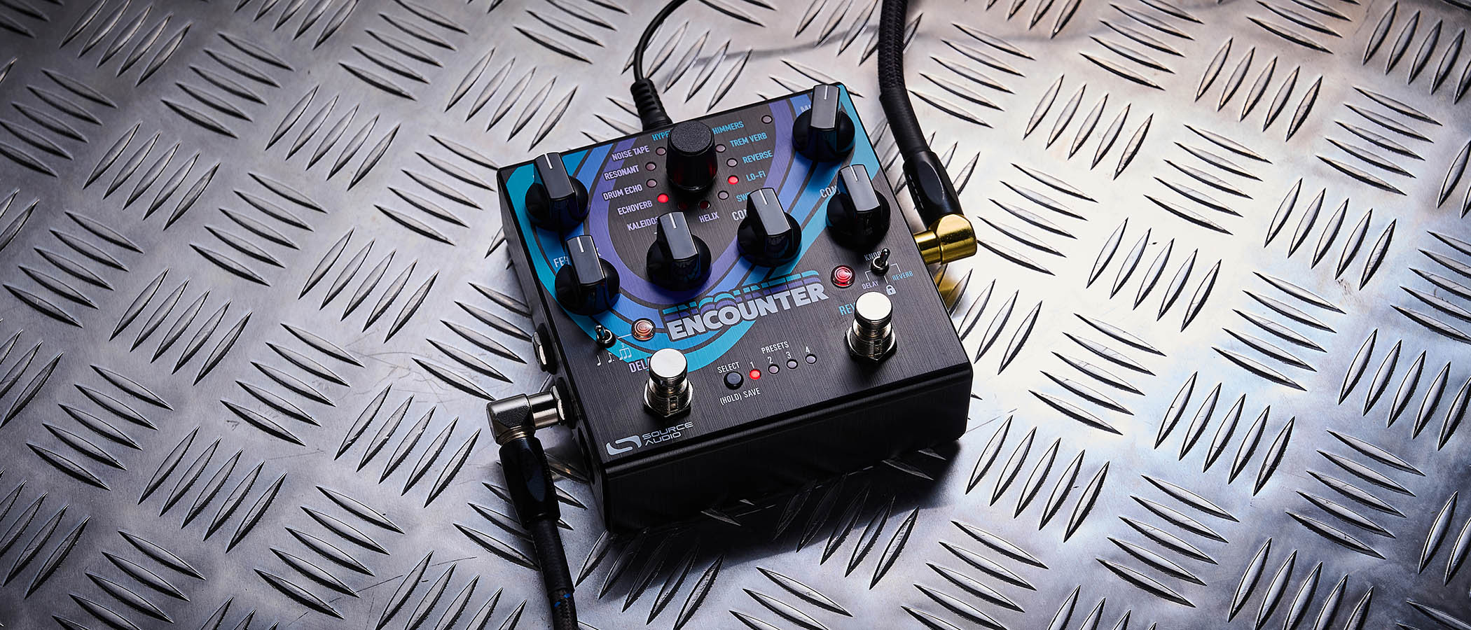 The Source Audio Encounter delay and reverb pedal is photographed here in close-up against an industrial metal background.