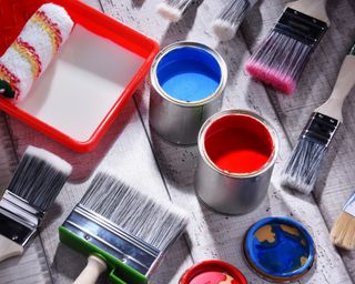 Colorful cans of paint and assorted brushes