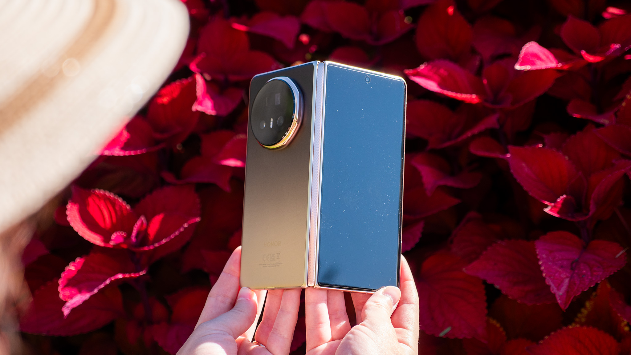 Holding the gold Honor Magic V5 open in front of red foliage