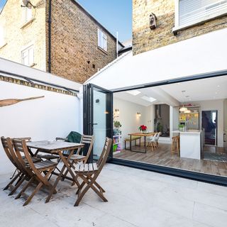 white rendered side return kitchen extension with bi-fold doors onto small patio