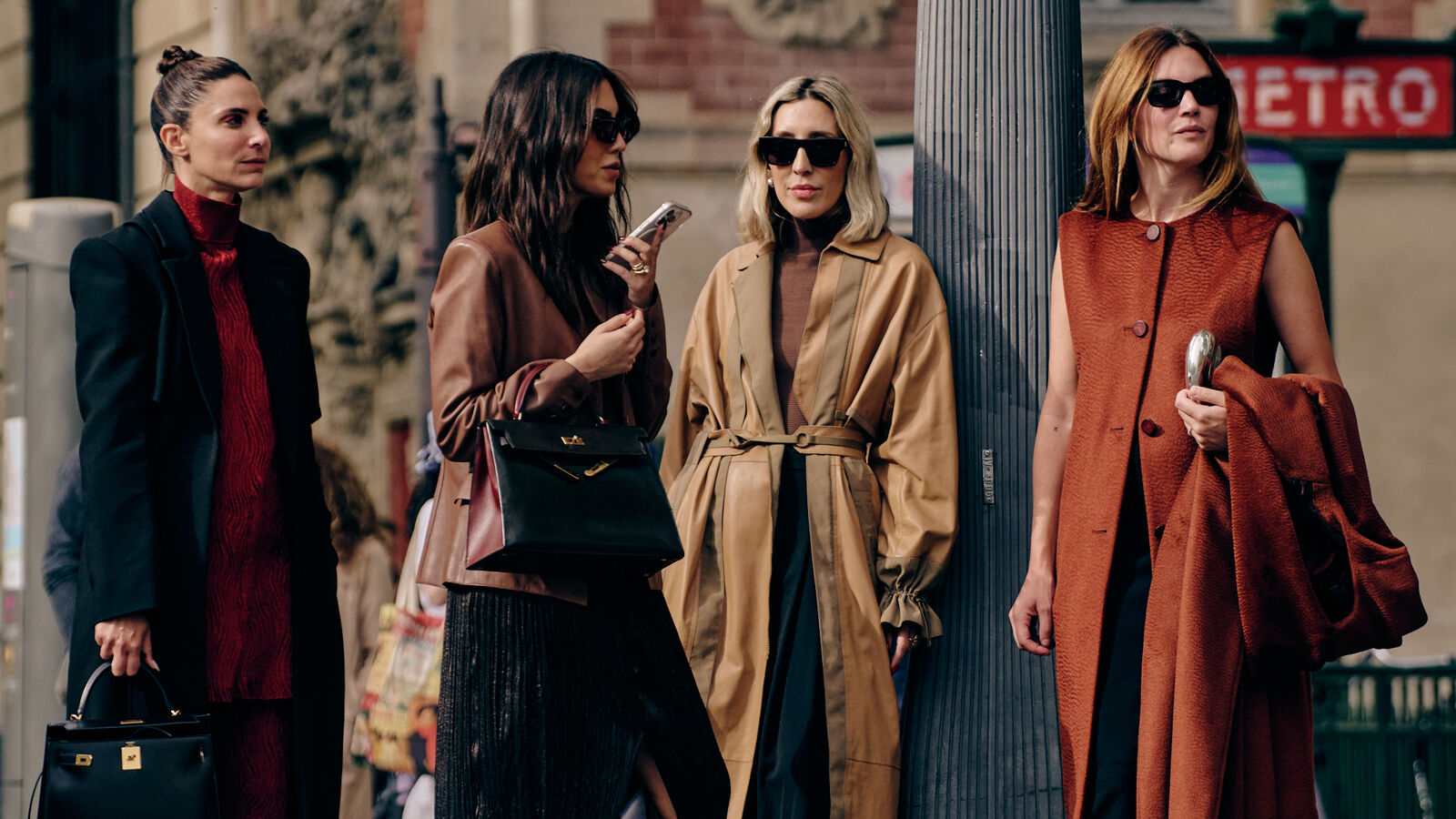 four women standing on the street at paris fashion week in trendy fall clothing