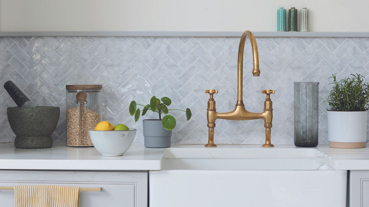 Grey kitchen with white worktop, grey mosaic tiled splashback and a belfast sink with brass vintage tap