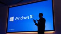 Former Microsoft Executive Vice President Terry Myerson stands in front of a presentation about Windows 10