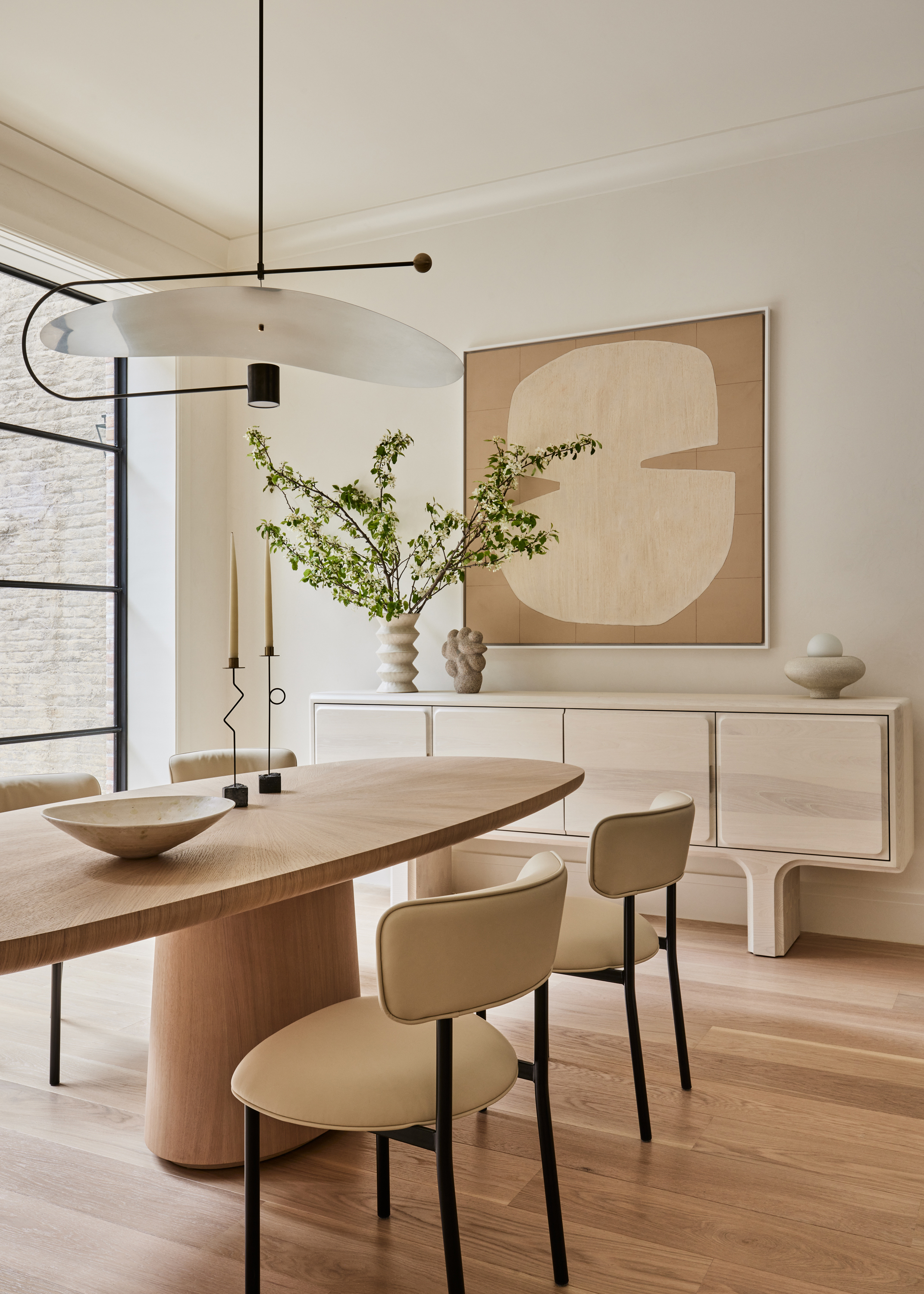 an offwhite dining room with beige accents, a wood dining table and floor with a sculptural ceiling light
