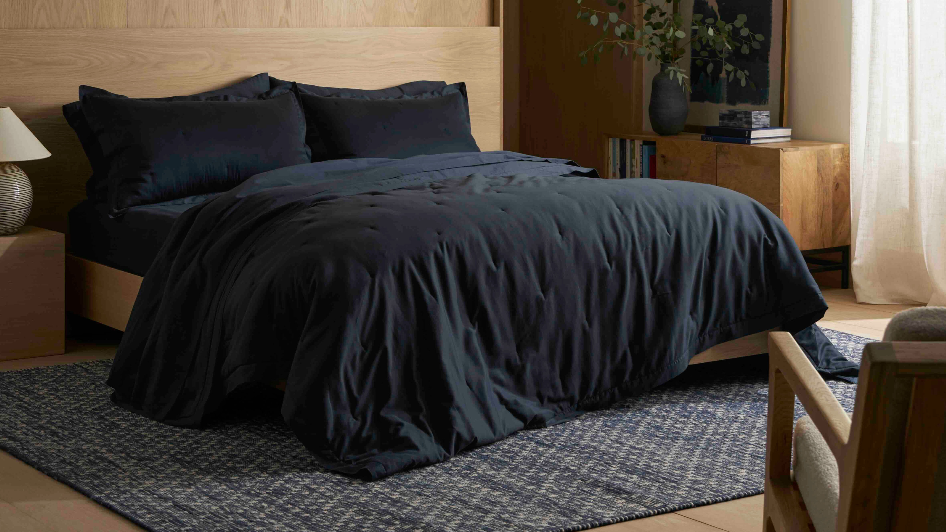 bed made with navy bedding, in a room with timber walls and floors