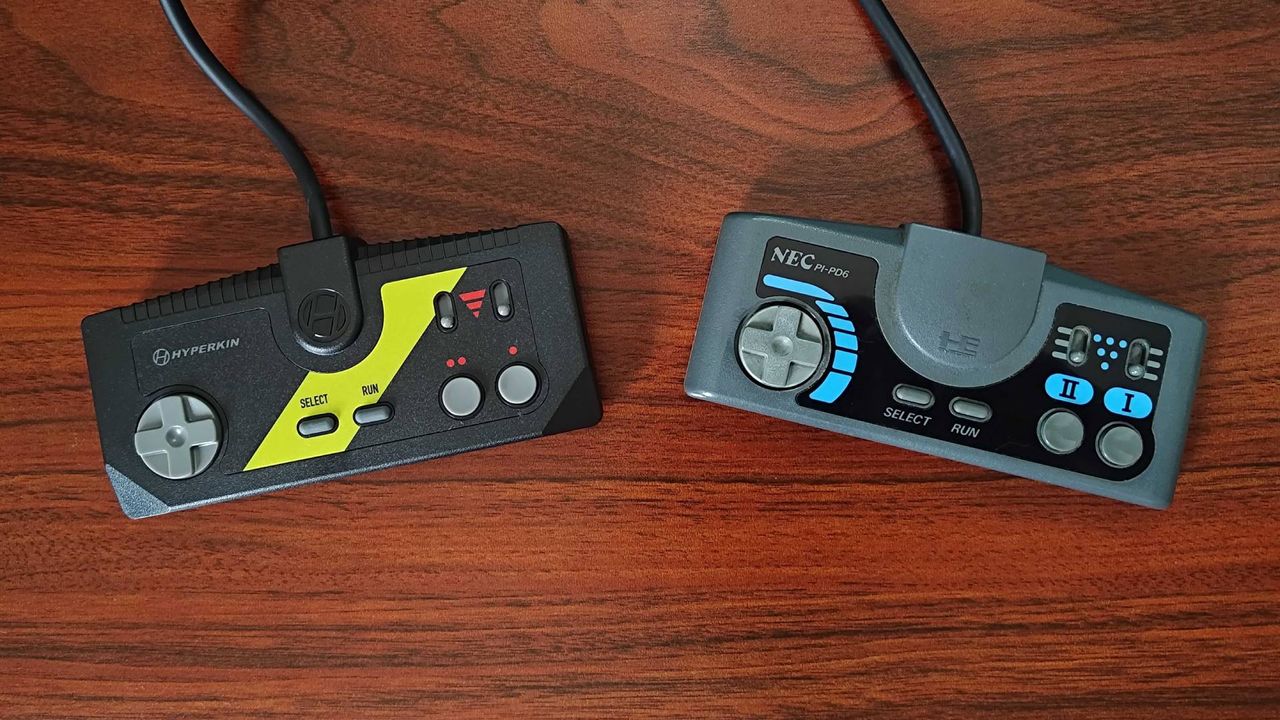 Hyperkin Retron GX controller next to PC Engine gamepad on woodgrain desk.