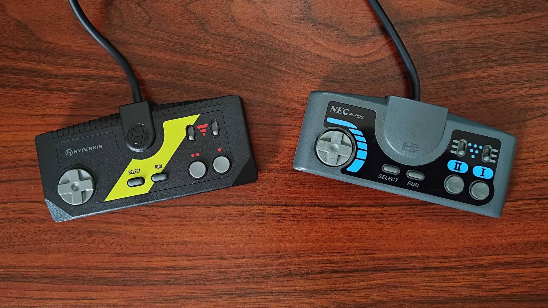 Hyperkin Retron GX controller next to PC Engine gamepad on woodgrain desk.