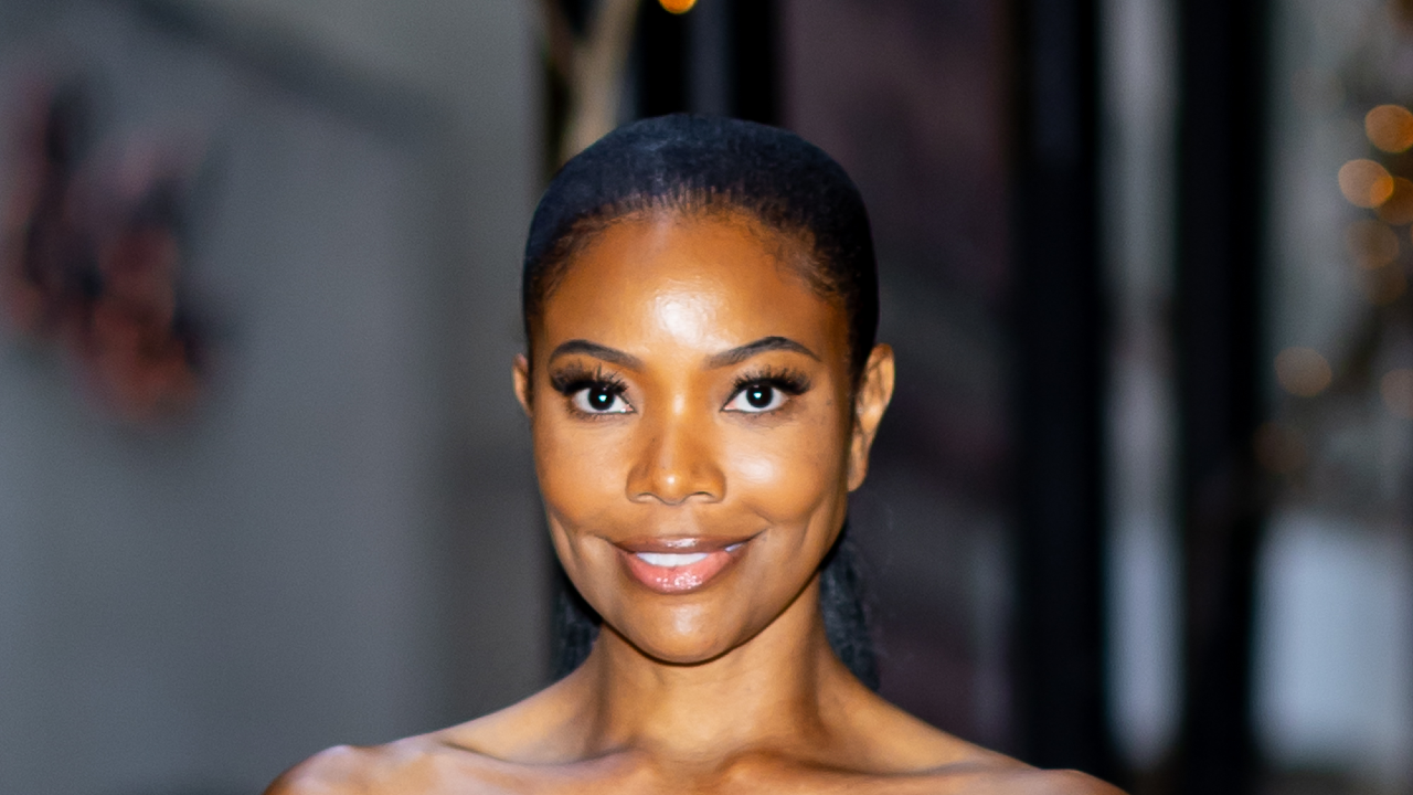 Gabrielle Union smiling at a camera and wearing a high ponytail.