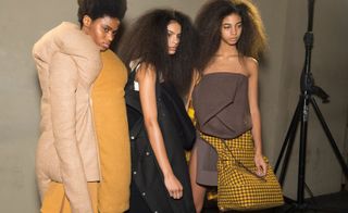 Left, model wears a yellow and beige cloud coat. Other models are seen wearing felt coats and folding tops. One model holds a yellow and brown check shoulder bag