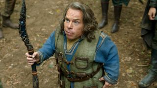 Warwick Davis holding a magical staff in the woods in Willow.