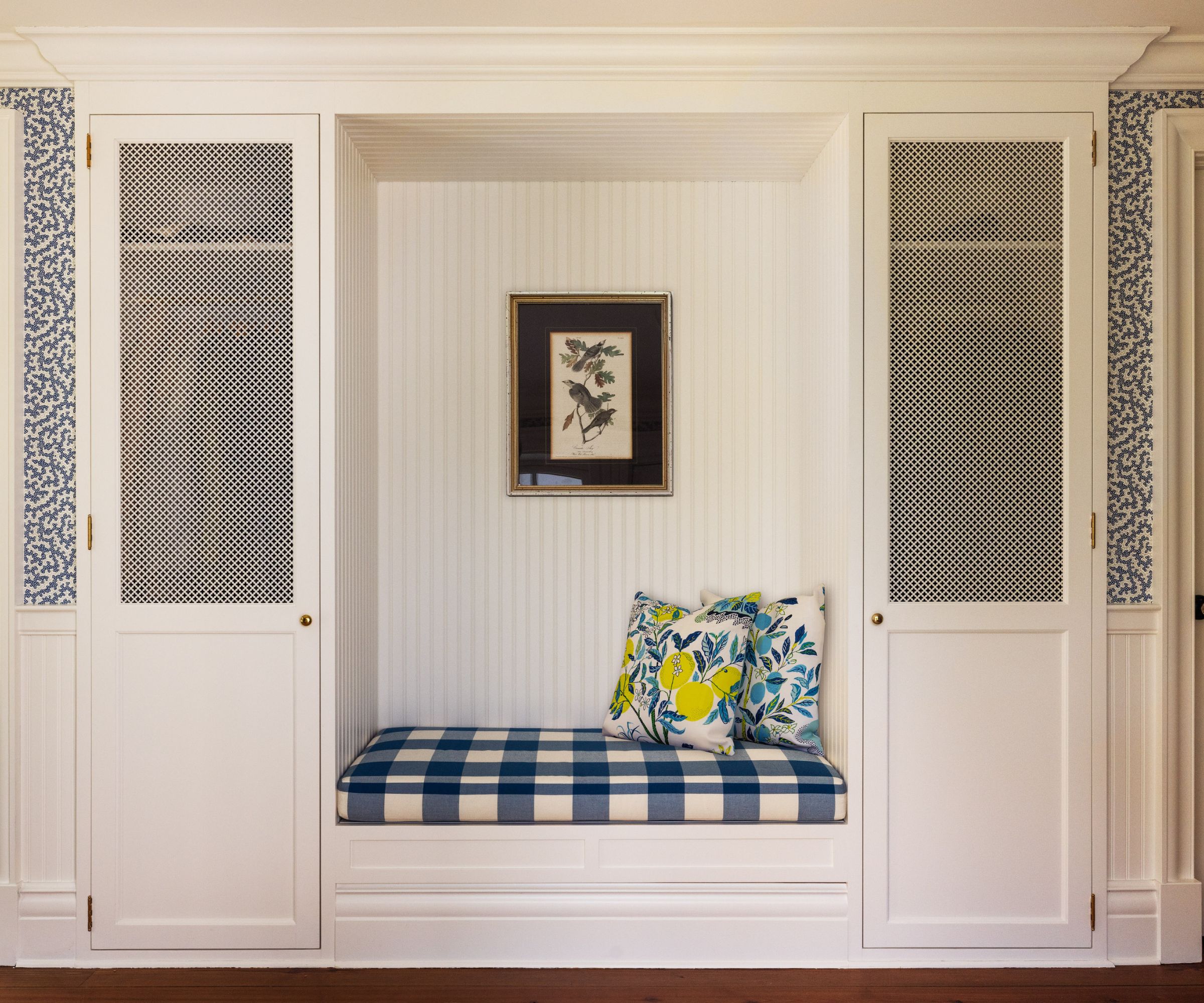 White wood paneled entryway with built in bench and blue and white cushions