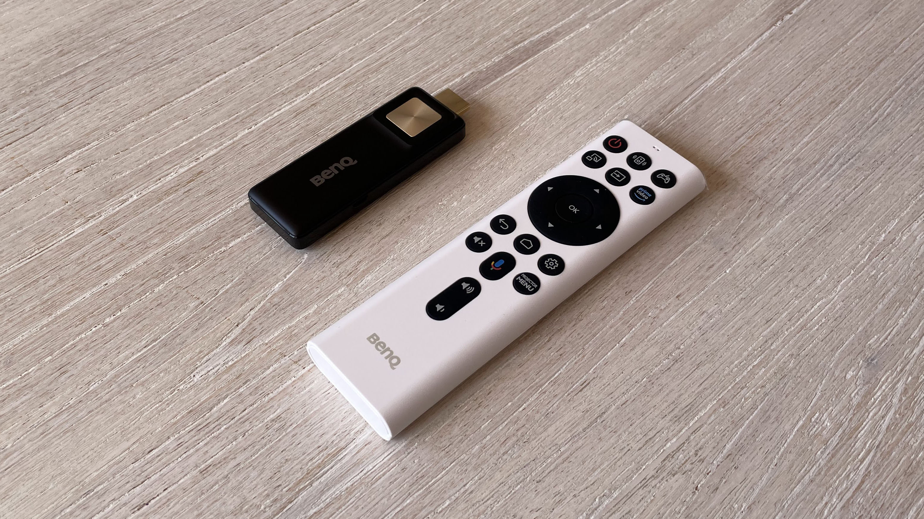 The BenQ X3000i gaming projector's remote control and Android TV dongle.