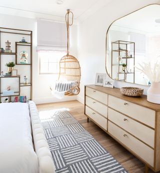 A bedroom with a long dresser and a long mirror above it