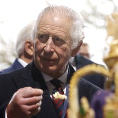 King Charles holding a spoonful of food in front of a crown cake