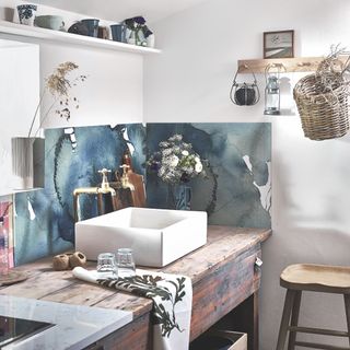 rustic kitchen with Belfast sink in freestanding unit, blue painterly splashback, white walls