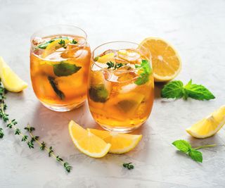 Two glasses of iced tea surrounded by lemon and mint
