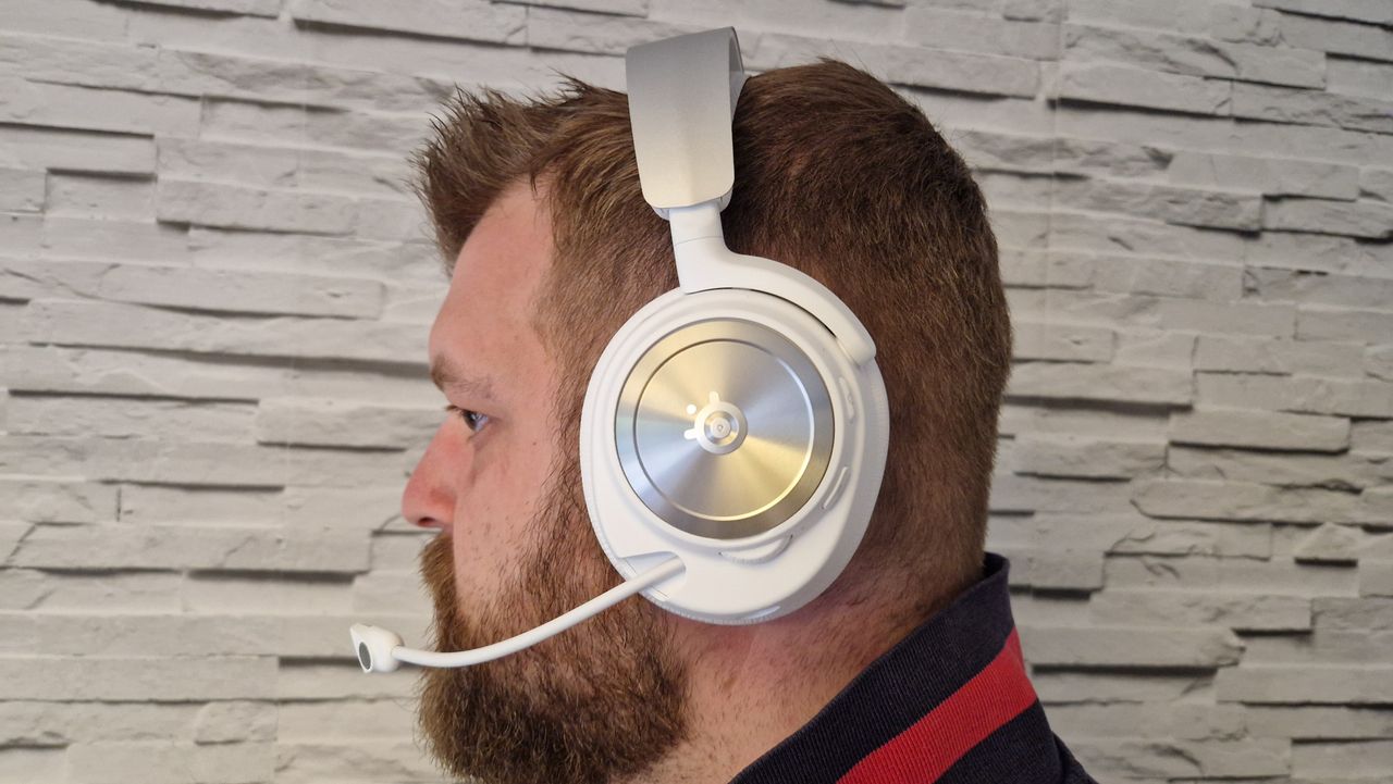 The SteelSeries Arctis Nova Pro Wireless white edition on a user's head with a white brick background