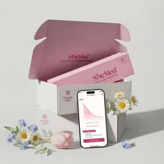 SheMed box and order containing SheMed products, with a phone displaying the SheMed app surrounded by flowers. 