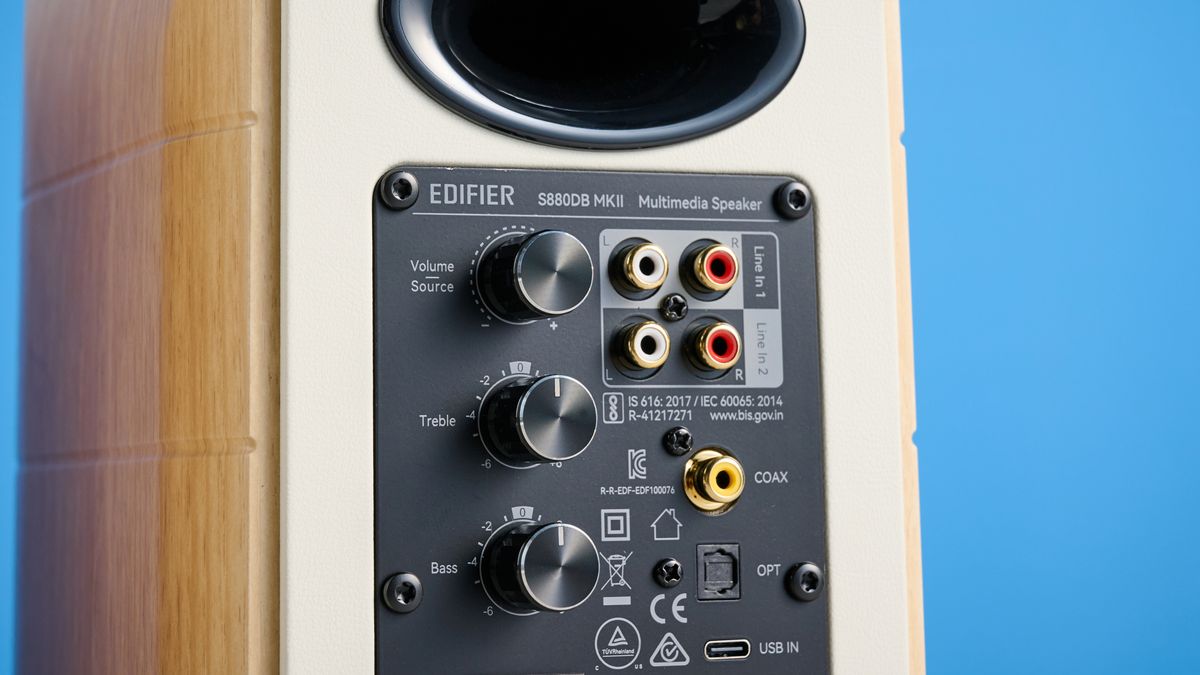 the edifier s880db mkii speakers in white and wood colorway showing the connectivity options, remote control, against a blue background
