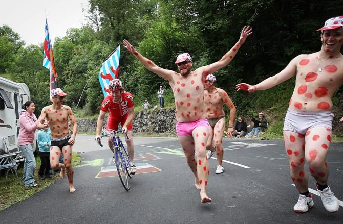 Polka dot-inspired fans run alongisde a tourist on his way up the climb