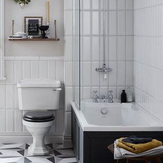 Bathroom with vertical white metro wall tiles and a dark grey panelled bath