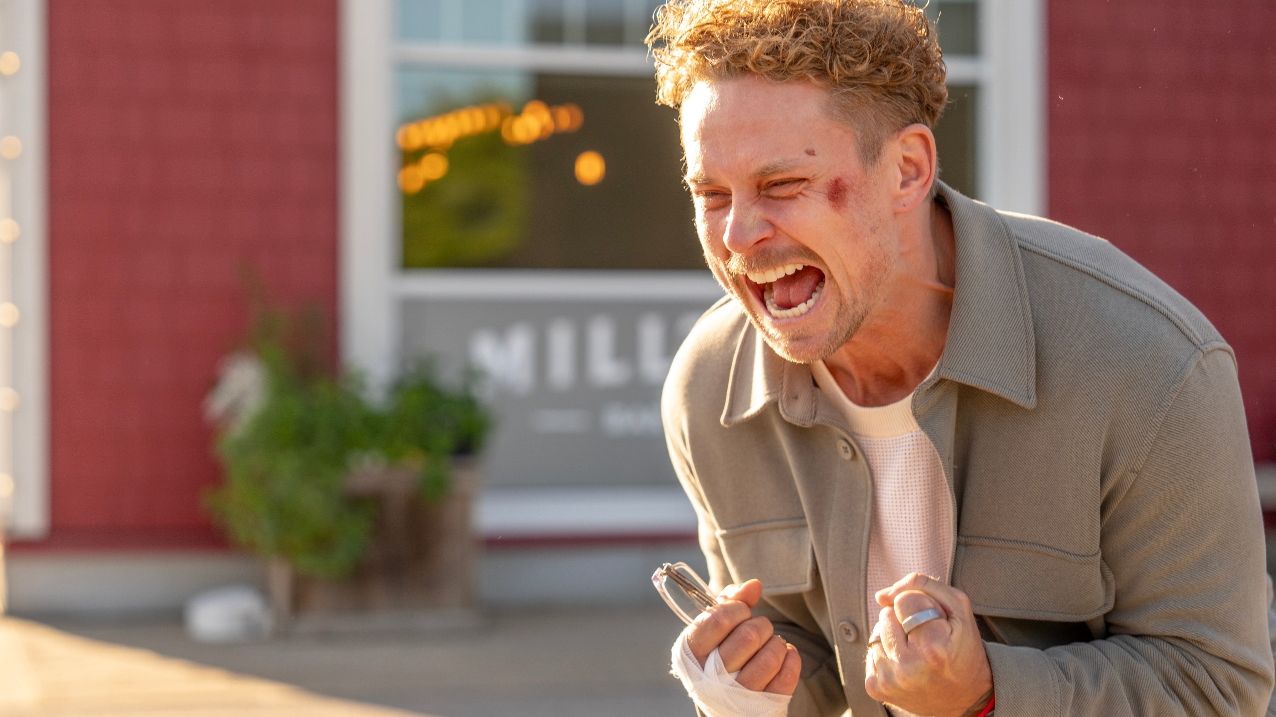 Billy Magnussen as Duncan screaming with his fists clenched. He has been wounded and has a bandage on his hand.