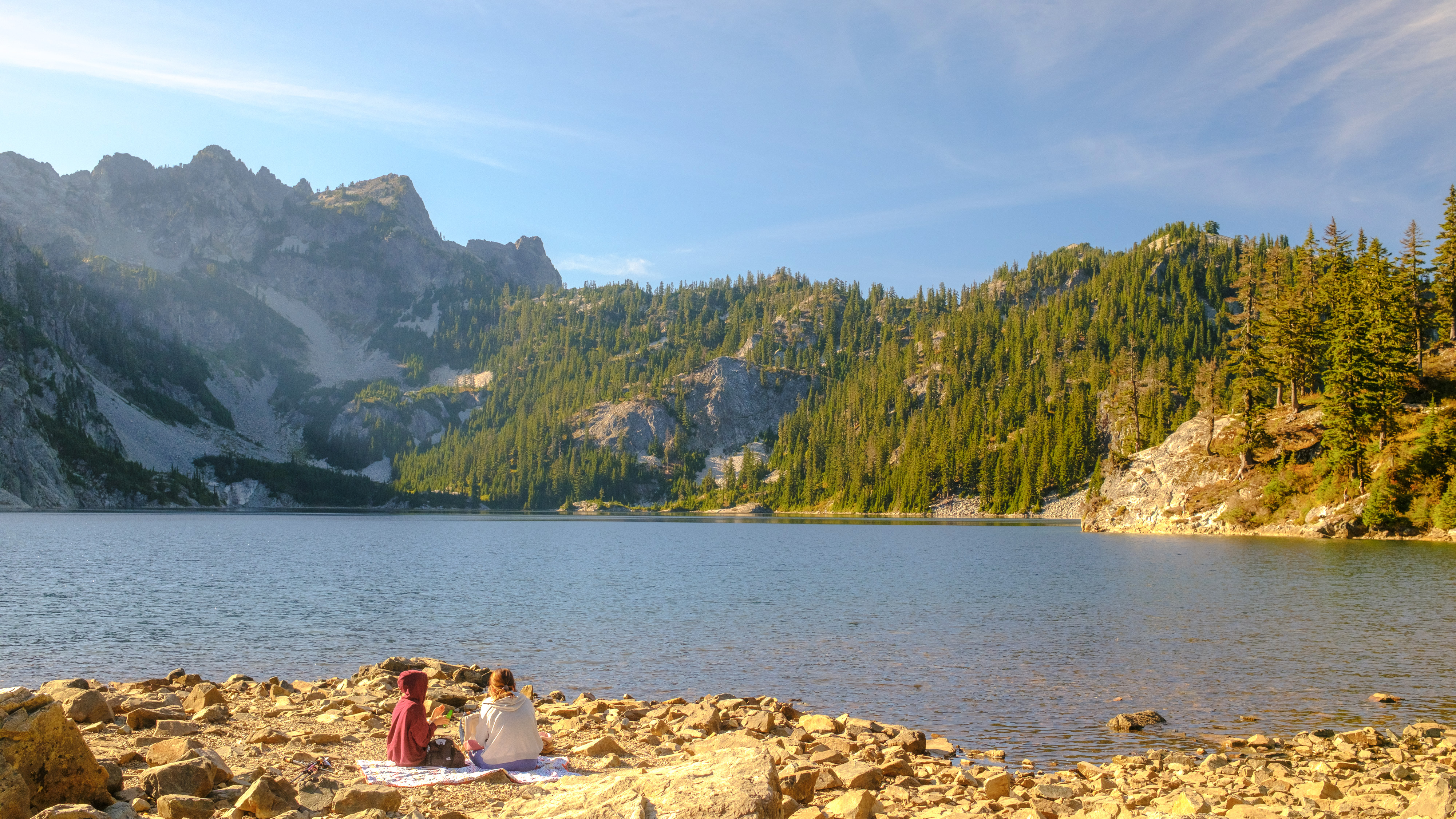 Washington'daki Cascade Dağları'ndaki Snow Lake patikasından ağaçları, zirveleri ve bir dağ gölünü gösteren manzaralar