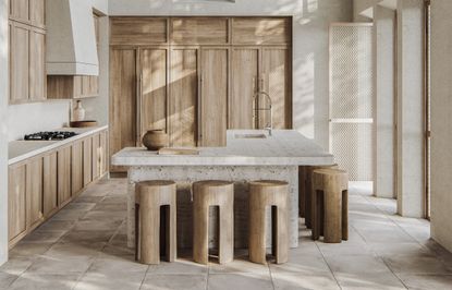 A kitchen with a marble countertop, and wooden cabinets and stools