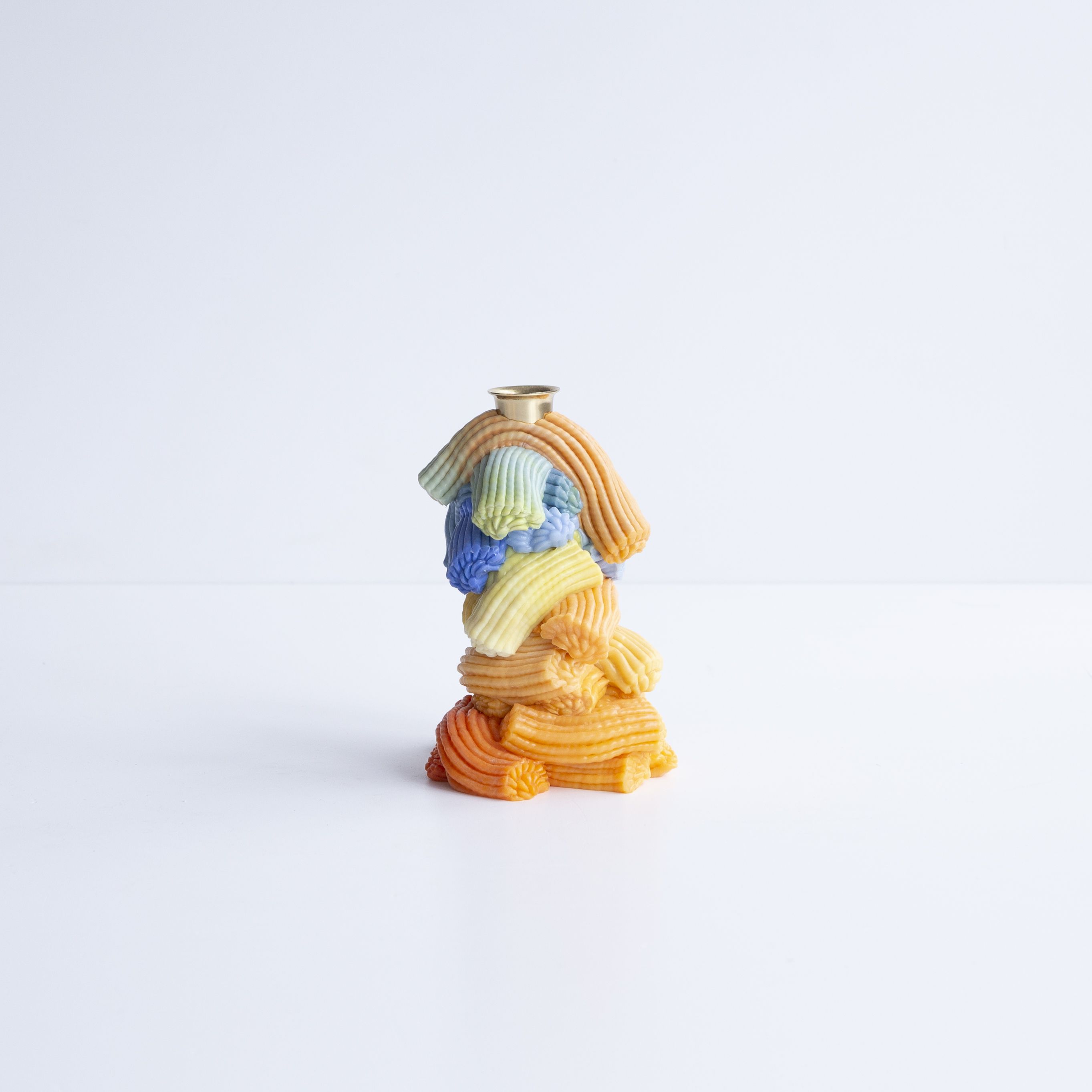 A series of squishy home objects designed from melted plastic and chrome or brass detailing, including a mirror, candelabra, and a kitchen towel rack.
