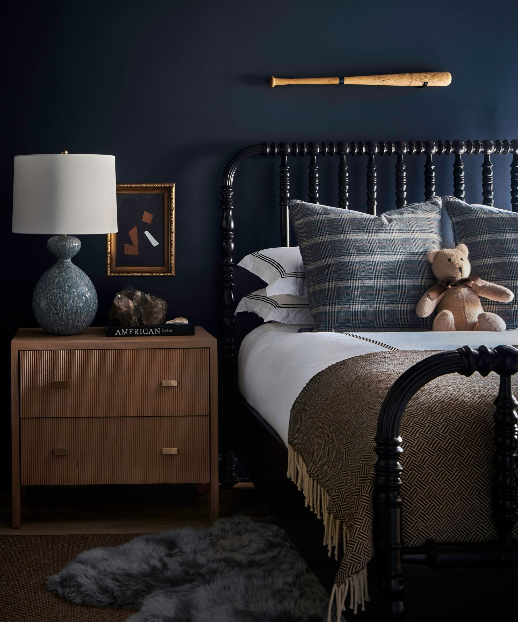 bedroom with dark navy wall, black bed frame and wooden nightstand