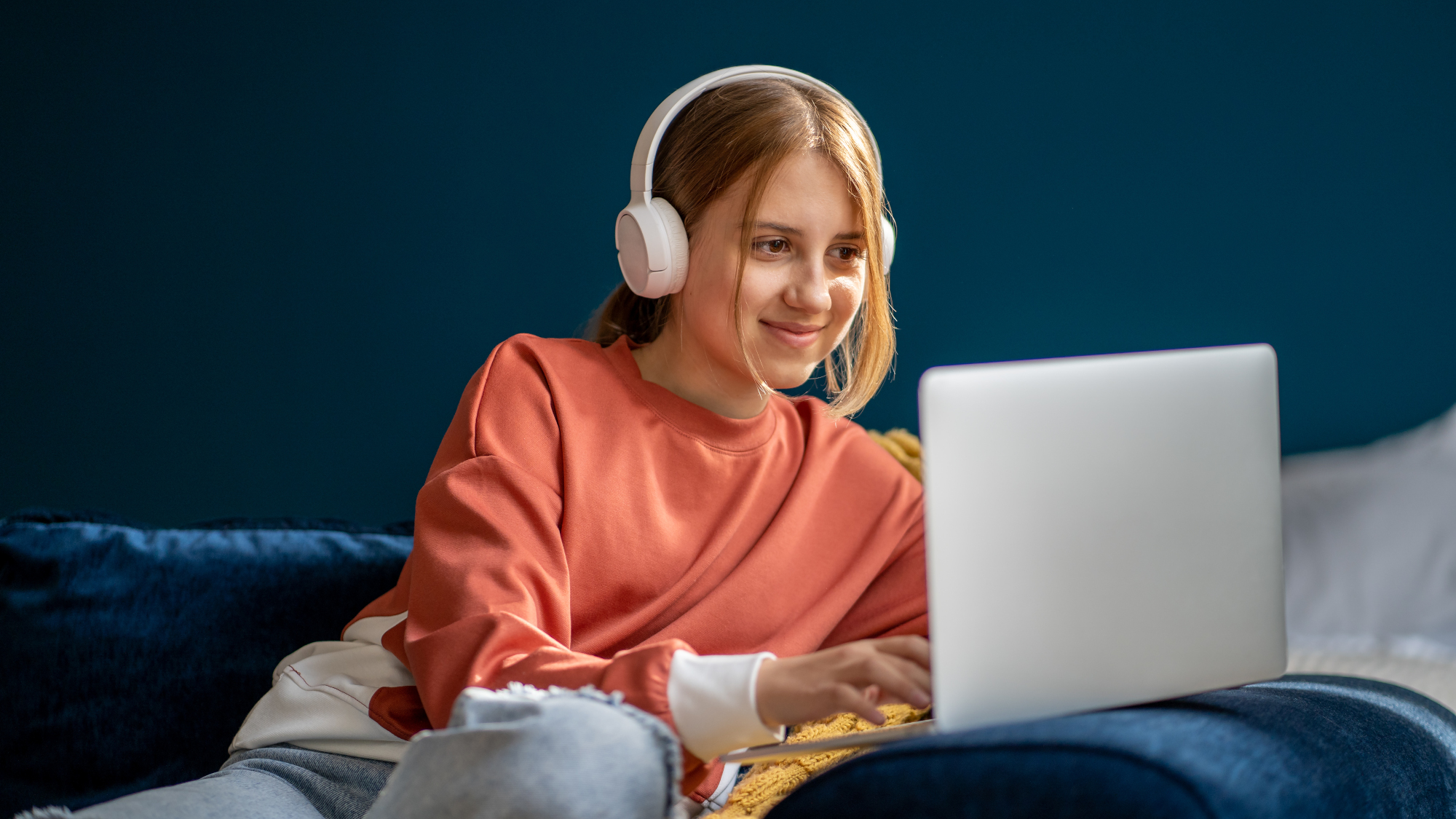 Girl wearing headphones, smiling using a laptop