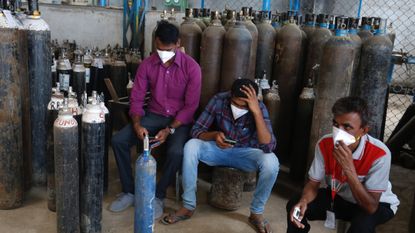 People wait to get their oxygen cylinders filled in Bengaluru, India