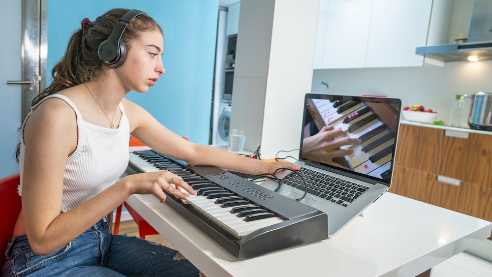 Girl playing keyboard connected to a laptop