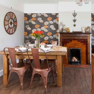 Dining area with wallpapered feature wall, wooden floors and wooden table with copper coloured chairs