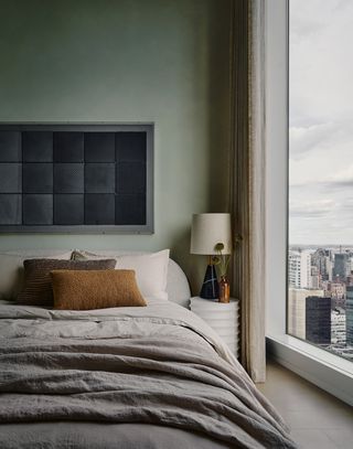 A contemporary artwork of black squares hangs above a bed made with gray and white sheets